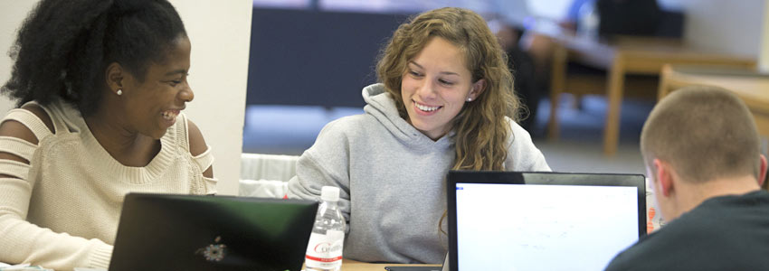 Students work together on their laptops in a study lounge