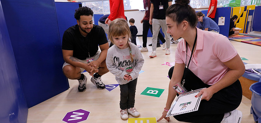 Two Physical Education majors working with a child in the Child Care Center on campus