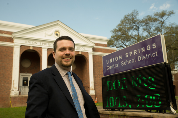 alumnus Jarett Powers standing in front of district office in Union Springs