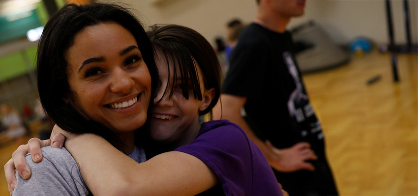 A Cortland student is embraced by a local youth participant in SUNY Cortland's specail olympics games.