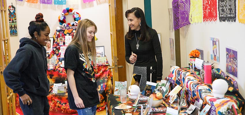 Students and professor looking at a Day of the Dead ofrenda.