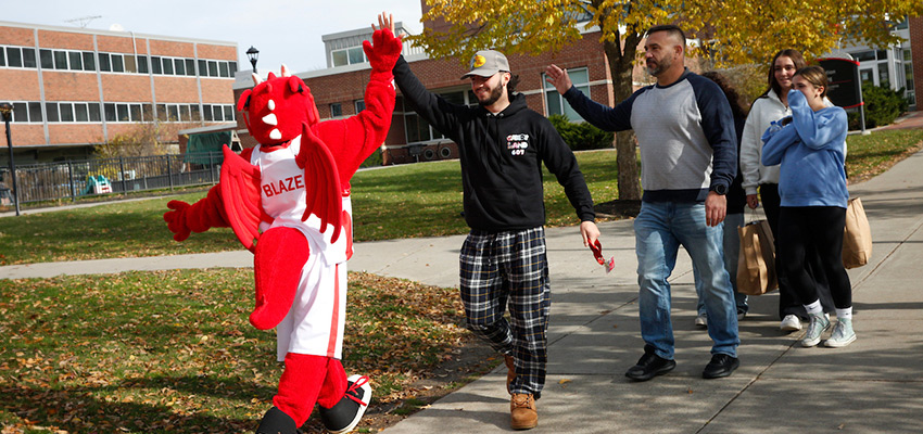 Family walking past Blaze the Dragon and giving the mascot a high five