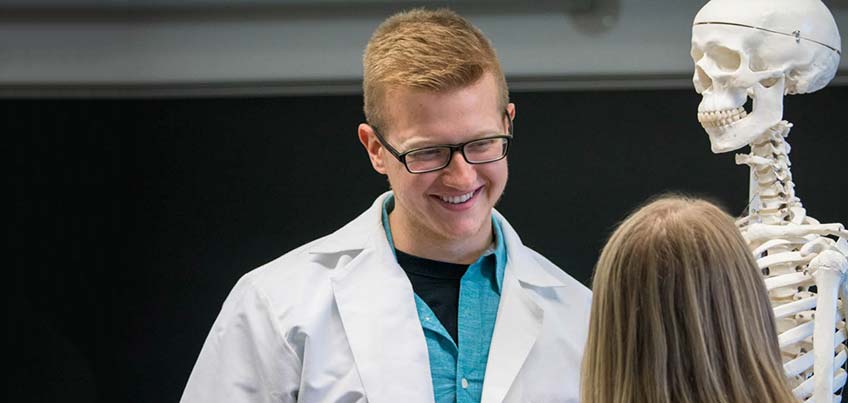 Pre-med Club member in white coat with skeleton