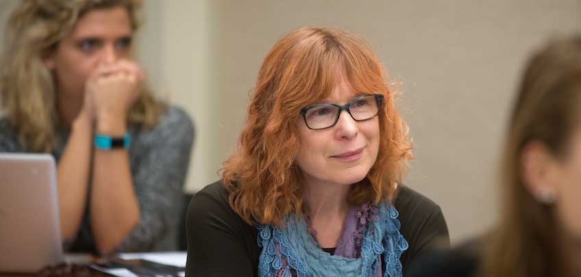 Graduate student sits in classroom lecture with peers