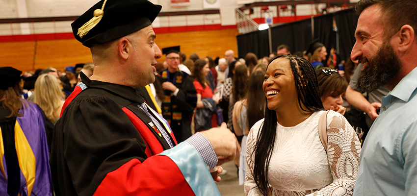 Student smiles and laughs with Assistant Professor Jeremy Jimenez of the Foundations and Social Advocacy Department