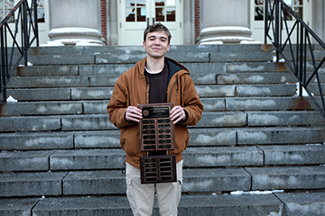 A representative from the COR 101-037 fundraising team holds their plaque.