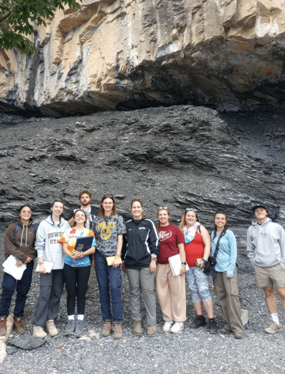 Group of students in Vermont posing in front of large rock structure