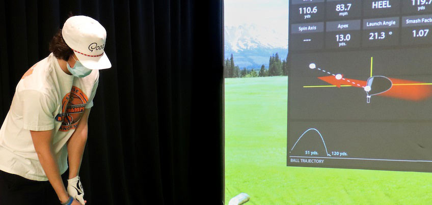 Student playing golf on simulator