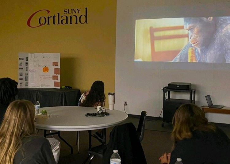 Students watching The Planet of the Apes at the Gorilla Corps showing, featuring a trifold about the environmental impact of Halloween.