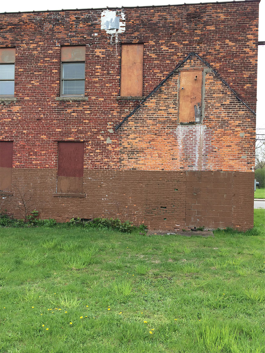 A brick facade showing several different iterations of adjacent or adjoining gable roofs that have since been removed.